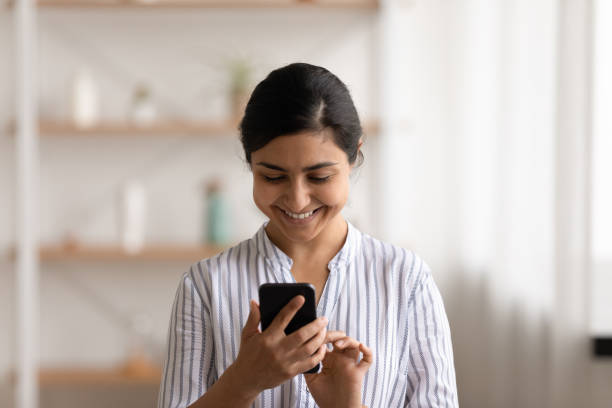 istock Head shot smiling Indian woman using smartphone, having fun 1331150902