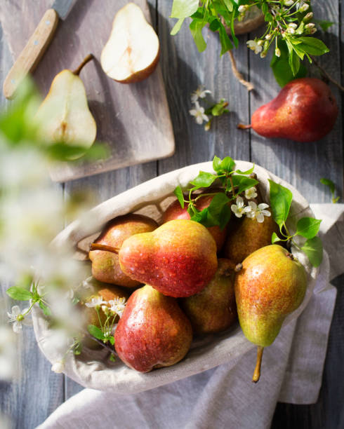 A fresh crop of pears. Flowering plants and food on a wooden table. Yellow fruits in a rustic style. In the process of making a pear pie Sweet fruits conference pear stock pictures, royalty-free photos & images