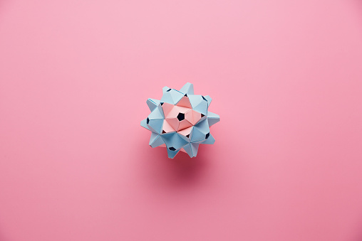 MulticolorÂ handmade modularÂ origami ball or Kusudama Isolated on pink background. Visual art, geometry, art of paper folding, paper crafts. Top view, close up, selective focus, copy space.