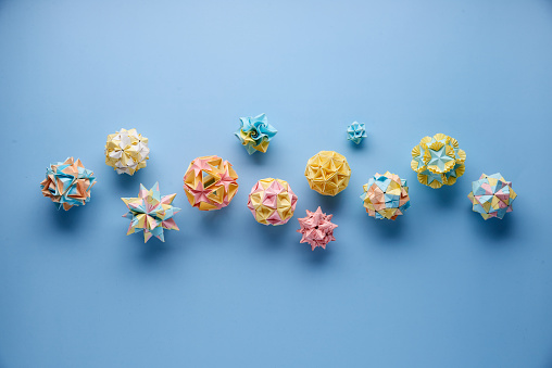 Set of multicolorÂ handmade modularÂ origami balls or Kusudama Isolated on blue background. Visual art, geometry, art of paper folding, paper crafts. Top view, close up, selective focus, copy space.