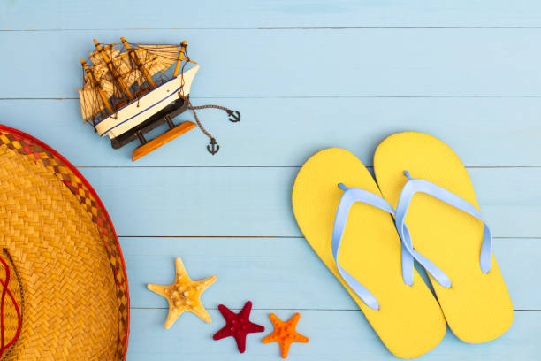 istock Summer time on a cool view on painted light blue wood table with sunglasses, flip flops, sailboat, hat and starfish 1331157753
