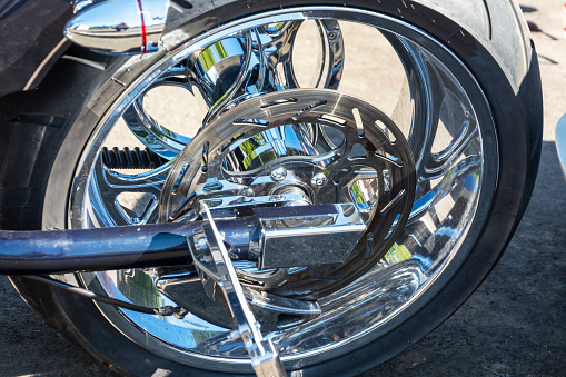 motorcycle brake disc on the rear wheel, brake caliper and tire, shining chrome.