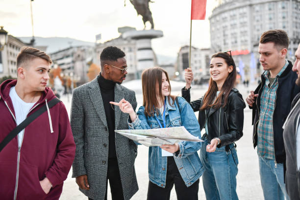 istock Smiling Female Pointing To Tour Group About Different Location To Visit On Map 1331160463