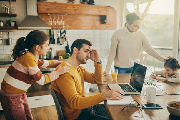 istock Exhausted father working on laptop while being with his family at home. 1331161399