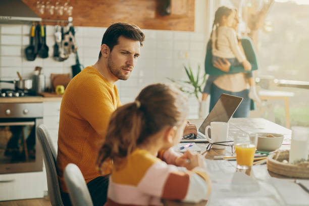 istock Young father working on laptop while talking to his daughter at home. 1331161428