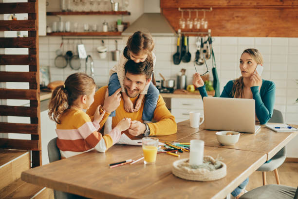 istock Happy father having fun with daughters while mother is working at home. 1331161433