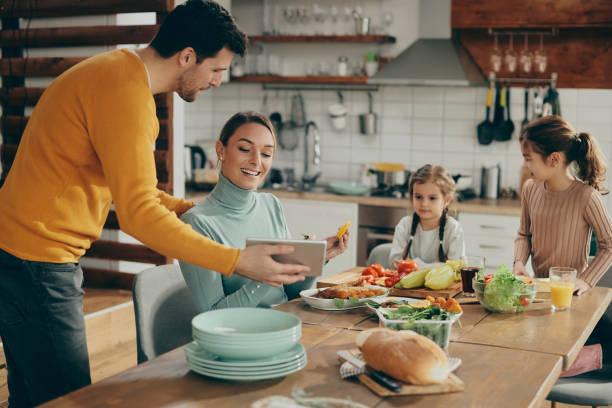 istock Happy parents using touchpad while preparing lunch with their daughters at home. 1331161474