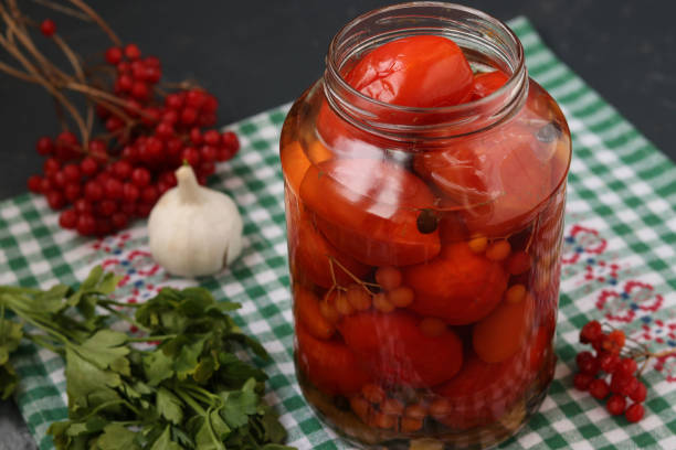 istock Marinated tomatoes with a viburnum in a open jar are located on a dark background 1331162513