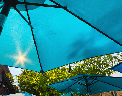 In Western Colorado Aqua Blue Colored Patio Umbrella with Sun Shining Through (Shot with iPhone 12 Pro Max 12mp 4032 × 3024 photos professionally retouched - Lightroom / Photoshop -downsampled as needed for clarity and select focus used for dramatic effect)