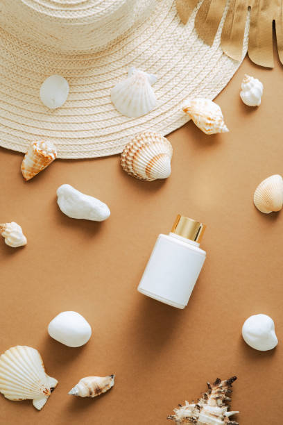 istock Suntan lotion bottle, seashells, straw hat on sand colored background. Flat lay, top view, copy space. Sunscreen beauty product packaging design 1331165282