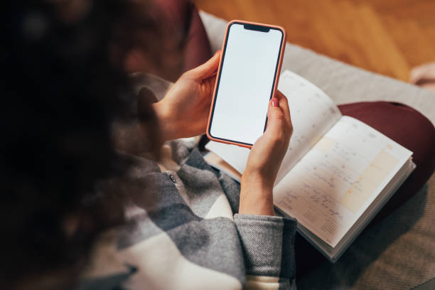 istock Empty Smartphone Screen Held by an Unrecognizable Woman Sitting on the Sofa 1331166345