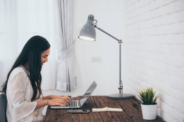 istock a asian girl work from home on laptop computer sitting at home, pick up call and write note 1331169104