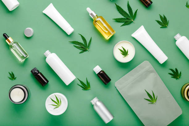 suero de aceite de cbd de cáñamo en botella de vidrio con hojas de cannabis, crema hidratante, suero, loción, aceite esencial. hoja de cannabis con producto cosmético para el cuidado de la piel patrón de puesta plana sobre fondo verde - beauty spa fotos fotografías e imágenes de stock