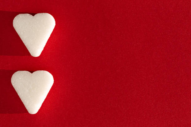 istock Two Sugar cubes, heart form on a red background with deep shadow. Love concept macro 1331171757