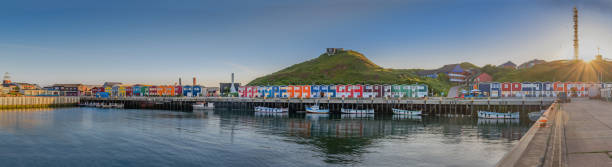 Hummerbuden typical colorful houses at evening on the shore on the island of Helgoland, Schleswig-Holstein, Germany. Hummerbuden typical colorful houses at evening on the shore on the island of Helgoland, Schleswig-Holstein, Germany.
Panorama view of Hummerbuden and harbour with sun flair. helgoland stock pictures, royalty-free photos & images