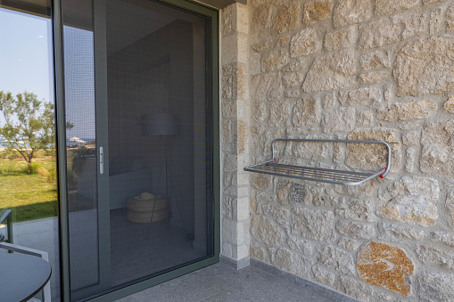 View of outdoor clothes dryer on patio of hotel room. Mosquito net protection on door. Greece.