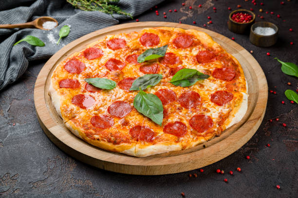 istock Pepperoni pizza with basil on wooden board on dark concrete table 1331174366