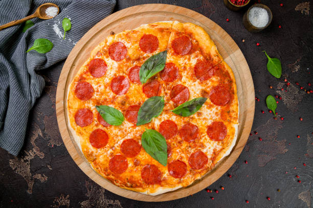 istock Pepperoni pizza with basil on wooden board on dark concrete table top view 1331175028