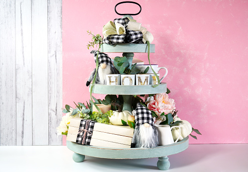 On-trend Farmhouse aesthetic three tiered tray decor filled with white pumpkins, cute black plaid gnomes, and farmhouse style stack of books mockup. Modern blush pink background.