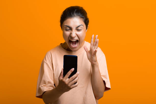 Portrait of yelling indian woman with mobile phone. Scream and social networking cleanliness tired hard work. stock photo