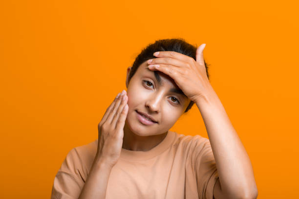 Close up portrait of young indian american woman doing facebuilding yoga face gymnastics yoga self massage. stock photo