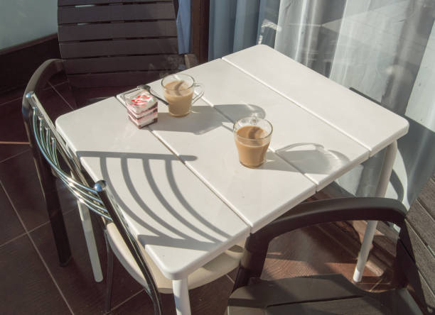 frühstück auf der balkonterrasse, außenbereich mit sonnenlicht und schatten, cremiges dessert mit erdbeermarmelade und kaffee mit milch. selektiver fokus. - snack coffee instant coffee cappuccino stock-fotos und bilder