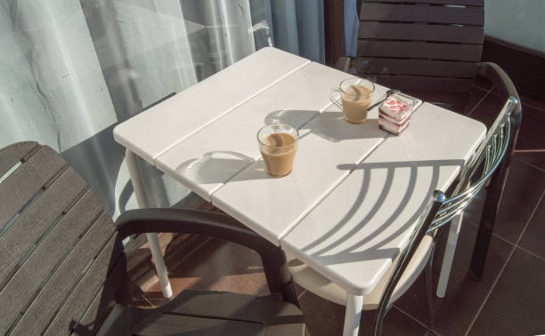 café da manhã no terraço da varanda, interior ao ar livre com luz solar e sombras, sobremesa cremosa com geleia de morango e café com leite. foco seletivo. - snack coffee instant coffee cappuccino - fotografias e filmes do acervo