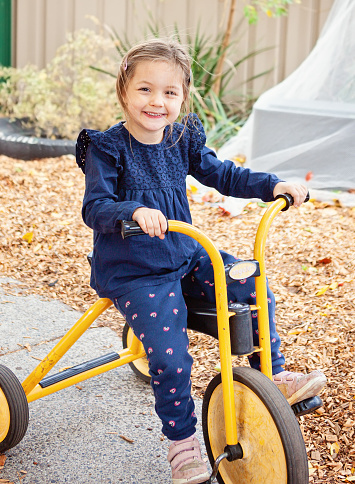 young happy girl on a tricycle