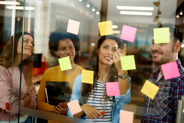 istock Group of web designers using sticky notes on a glass wall during a meeting 1331204750