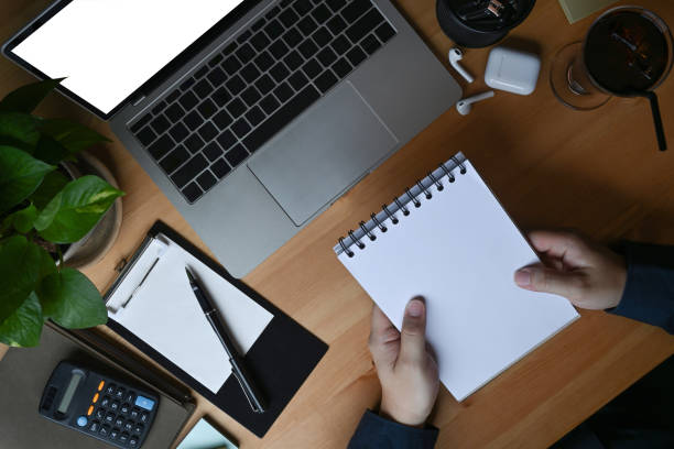 istock Businessman holding notebook and using laptop on wooden table. 1331215549