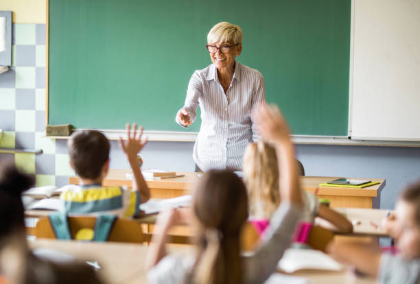 istock Happy senior elementary teacher aiming at school kid to answer her question. 1331216276