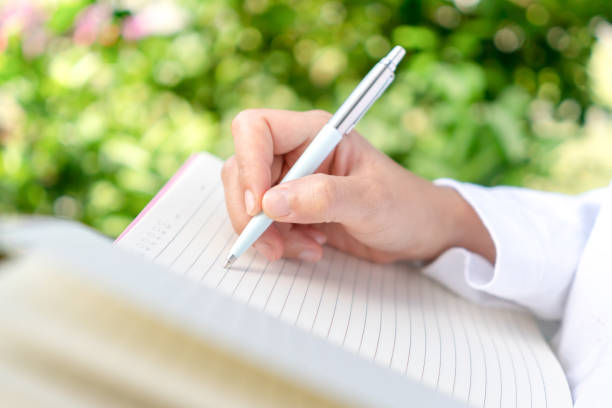 istock Woman hand writing down in small white memo notebook for take a note not to forget or to do list plan for future. 1331217029