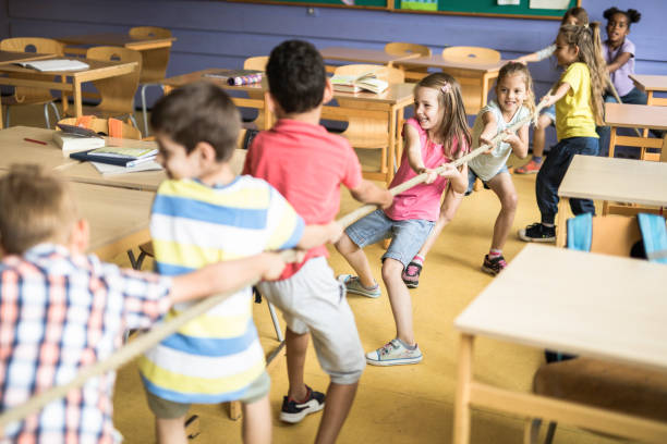 istock Playful elementary students playing tug-of-war in the classroom. 1331217067