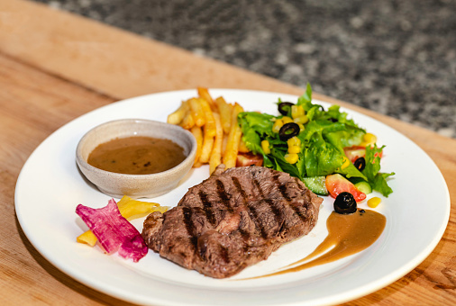 A White Plate of Medium Rare Beefsteak served with French Fried and Salad\nTop Blade