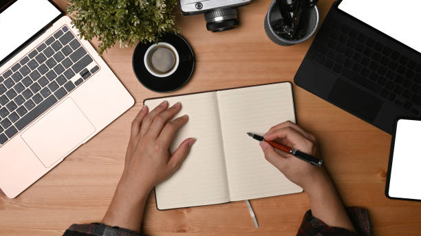 istock Man photographer writing something on notebook at his workspace. 1331218388