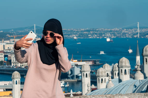 uma mulher muçulmana elegante tira uma selfie perto da mesquita suleymaniye. - people portrait mobile - fotografias e filmes do acervo