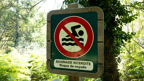 No bathing sign prohibited and risk of drowning text in french means baignade interdite risque de noyade on beach river