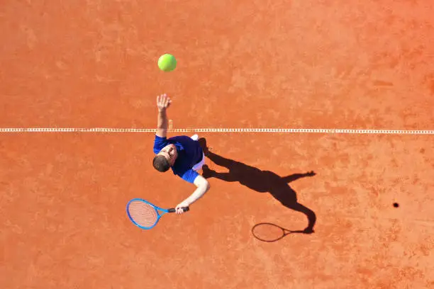 Aerial view of a professional tennis player performing powerful first serve with a jump rebound