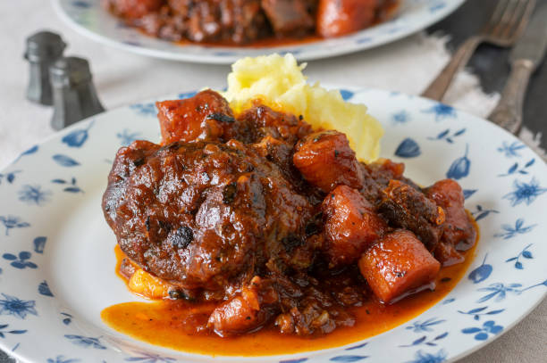 Braised beef shanks Delicious fresh and homemade cooked ossobuco. Italian braised beef shank with savory gravy and vegetables. Served with mashed potatoes on a plate. Closeup and front view with blurred background ossobuco stock pictures, royalty-free photos & images