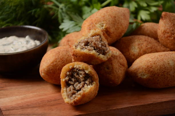 istock Deep fried kibbeh of ground beef meat mixed with bulgur, stuffed with fried minced meat with pine nuts on a clay plate on wooden board 1331237435
