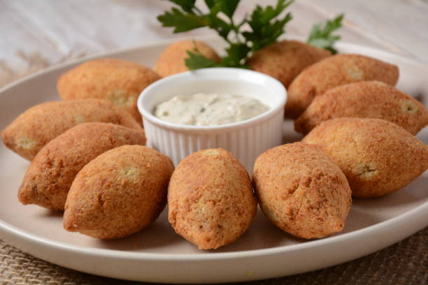 istock Deep fried kibbeh of ground beef meat mixed with bulgur, stuffed with fried minced meat with pine nuts on a clay plate on wooden table 1331237464