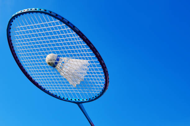 istock Badminton racket with shuttlecock against blue sky. Badminton open air game activity. Badminton outdoor sport playing. Close up view with copy space. 1331240387