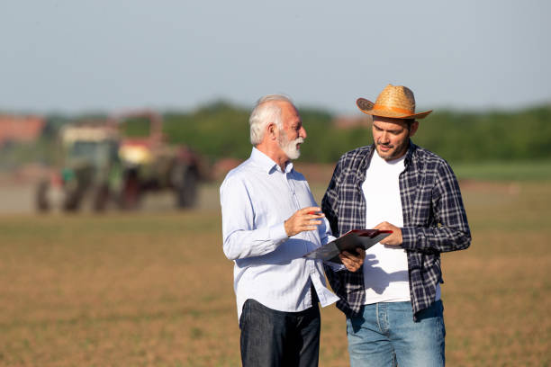 Farmer and insurance sales representative talking in field stock photo