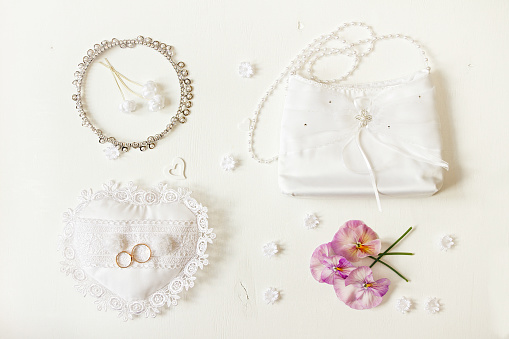 Wedding background. Bride accessories: rings, handbag, boutonniere, necklace. Top view.