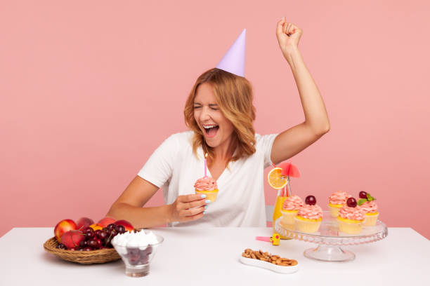 Photo of Excited blonde young adult female celebrating birthday, holding cake with candle, yelling happily, enjoying dream come true on her holiday.