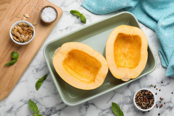 istock Raw spaghetti squash halves in baking dish with basil and spices on white marble table, flat lay 1331242523