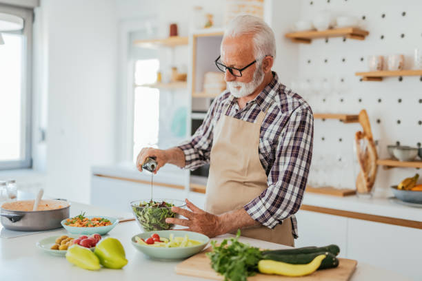 istock Senior man making salad at kitchen counter 1331243165