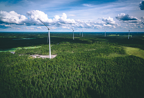 Windmills. Aerial view of windmills in green summer forest in Finland. Wind turbines for electric power with clean and Renewable Energy