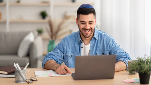 istock Smiling israeli man working on laptop at home 1331245237