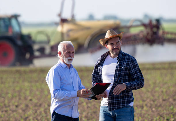 istock Farmer and insurance agent talking in agricultural field in spring 1331245357